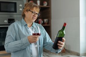 Kobieta pije wino w kuchni