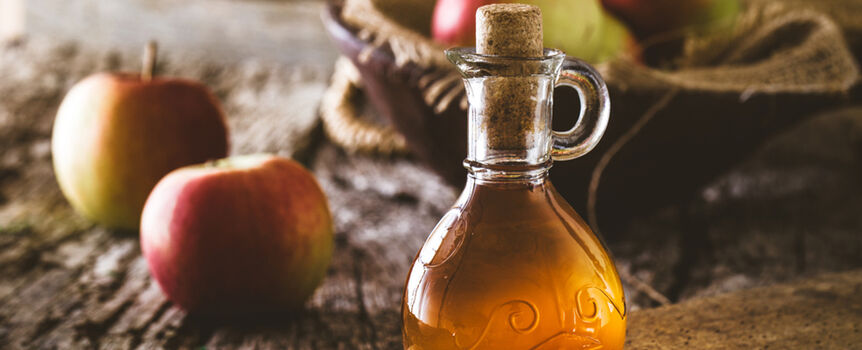 Ocet jabłkowy stoi na tle jabłek